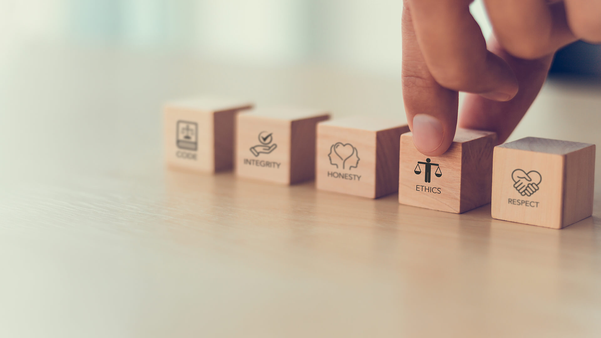 Una mano allinea cubetti di legno con le scritte integrità, onestà, etica e rispetto